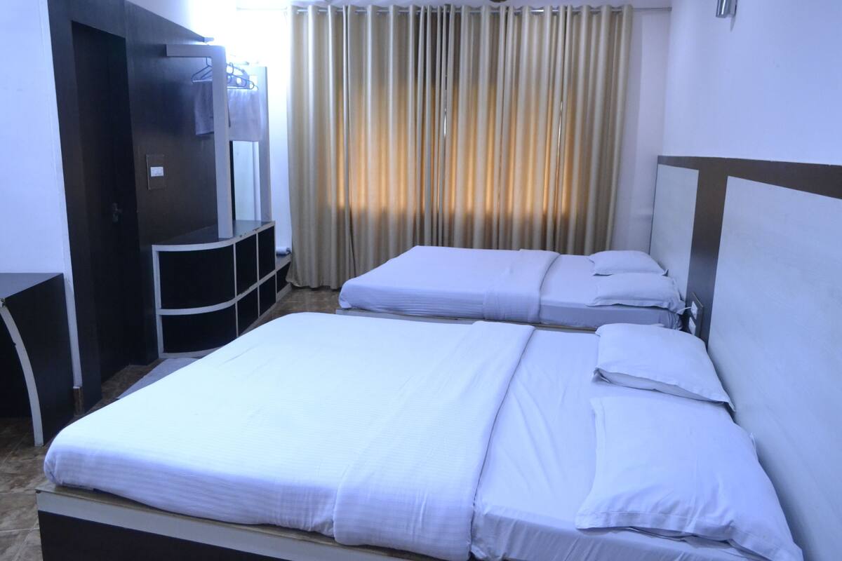 A hotel room with two beds, a desk, and a mirror.