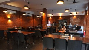 Un restaurante con paredes de ladrillo, varias mesas y sillas, lámparas colgantes y un equipo de aire acondicionado.