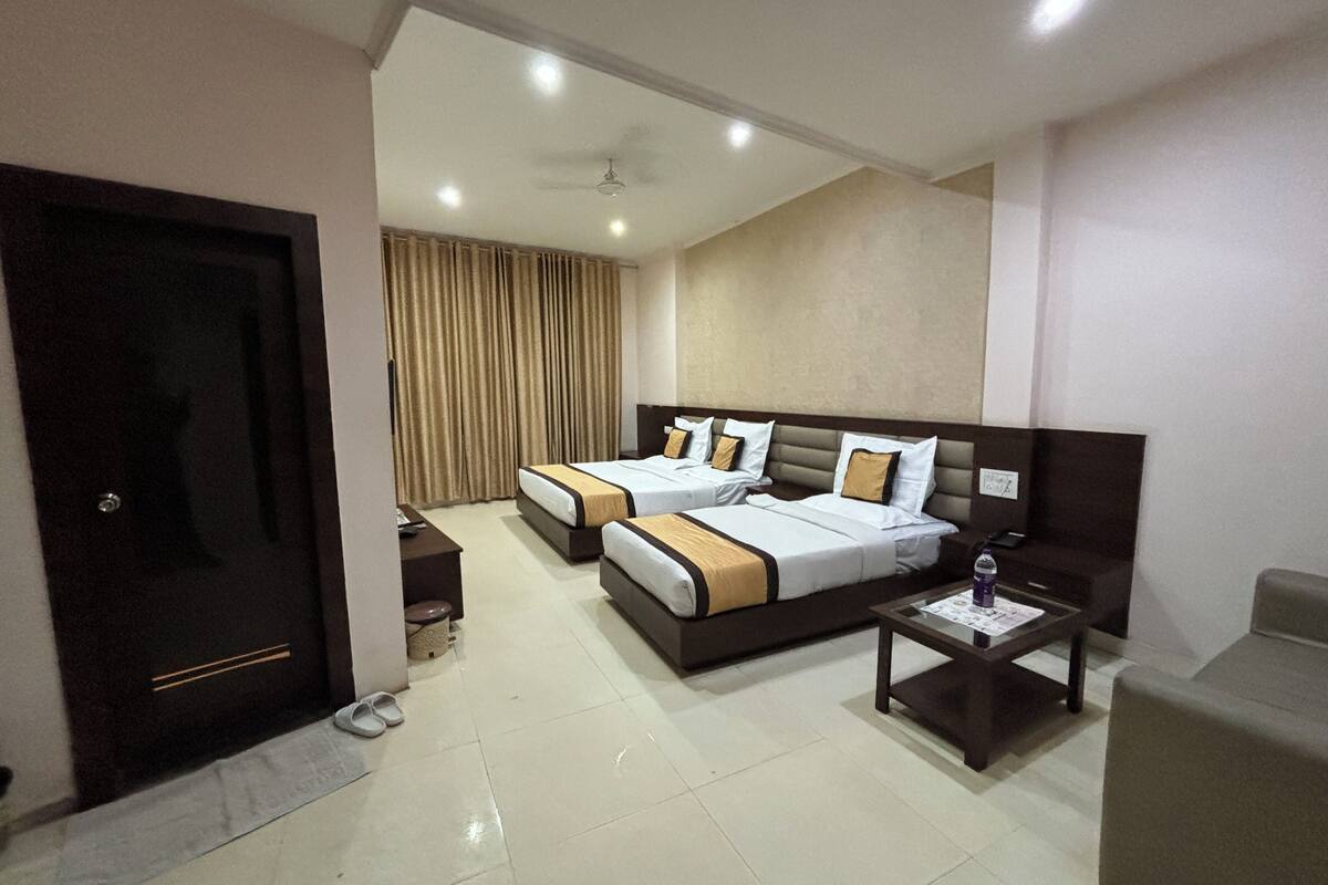 A hotel room with two beds, a desk, a chair, and a small table.