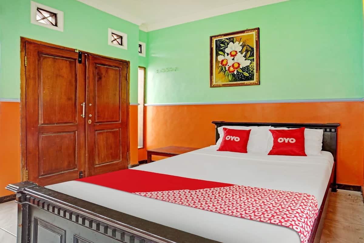 A bedroom with a bed, a wardrobe, and a painting on the wall.