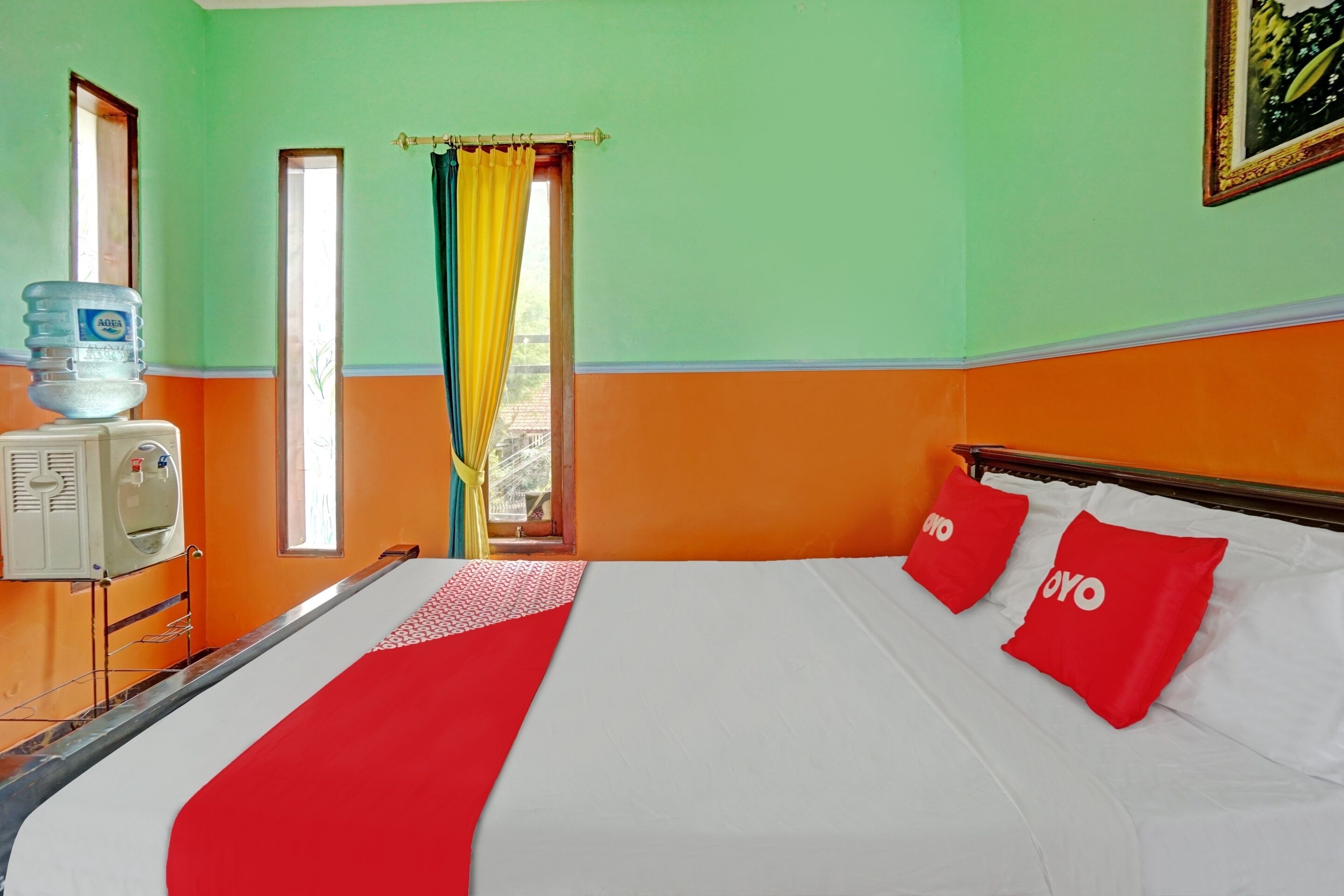 A hotel room with a bed, a water dispenser, and a window with curtains.