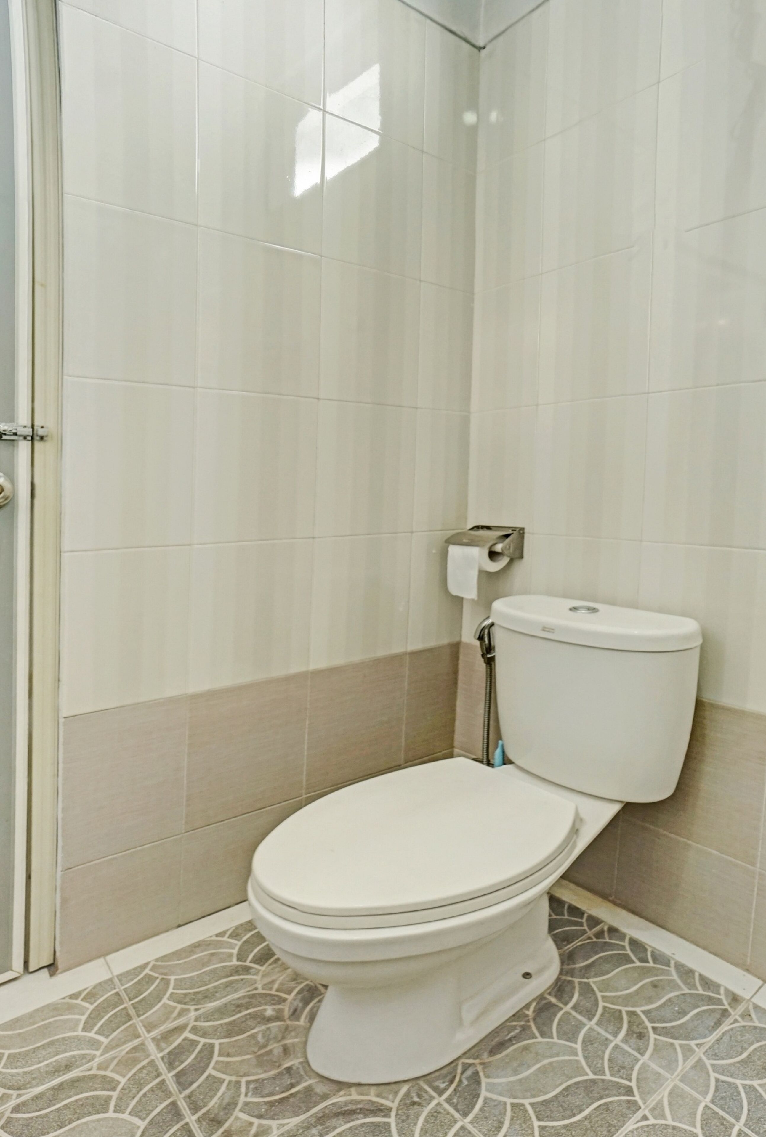A bathroom with a toilet, a shower, and a tiled floor.