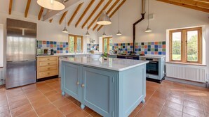Una cocina amplia con una isla grande, vigas de madera y un revoque de azulejos.