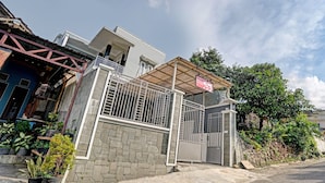 A residential building with a gated entrance, a covered porch, and potted plants. - OYO Life 90472 Villa Dua Dua (Batu)