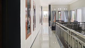 A corridor with a polished floor, a railing, and a view of the outside. - OYO Life 90472 Villa Dua Dua (Batu)