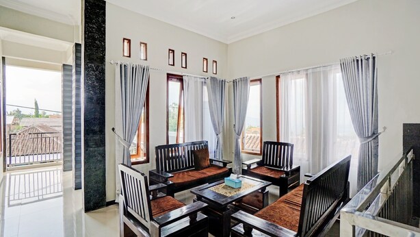 A spacious living area with a high ceiling, multiple seating arrangements, and large windows with curtains. - OYO Life 90472 Villa Dua Dua (Batu)