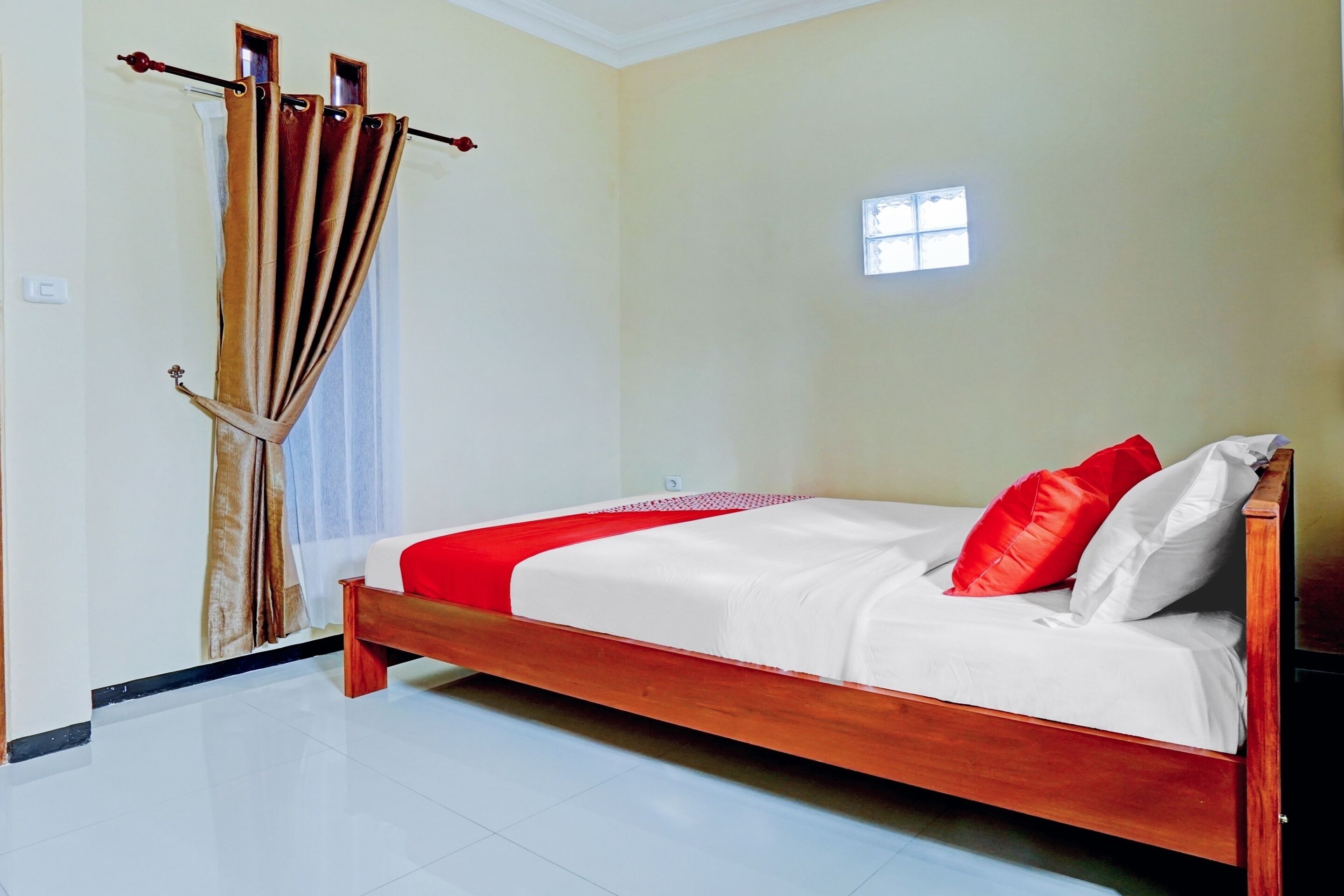 A bedroom with a wooden bed, white bedding, and a red throw.