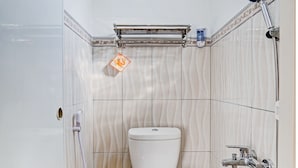 A small bathroom with a toilet, a shower, and a towel rack. - OYO Life 90472 Villa Dua Dua (Batu)
