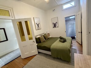 A bedroom with a bed, a door, and framed pictures on the wall. - Sunny Apartment in Surry Hills (Surry Hills)