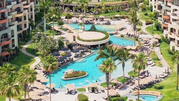A resort with multiple swimming pools, palm trees, and sun loungers.