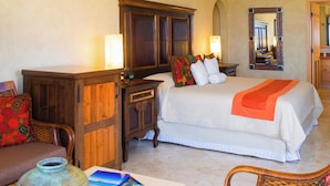 A hotel room with a bed, bedside tables, a dresser, a chair, a table, a vase, and a ceiling fan.