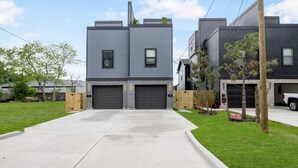 A modern two-story house with a garage, a well-maintained lawn, and a clear sky. - Contemporary-3 Bedroom-Rooftop in the Heart of Downtown Conroe (Conroe)