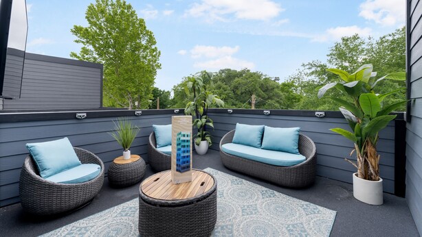 A rooftop patio with wicker furniture, a wooden coffee table, and potted plants. - Contemporary-3 Bedroom-Rooftop in the Heart of Downtown Conroe (Conroe)