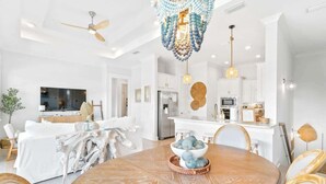 A modern living room with a round wooden table, white sofas, and a dining area. - Watersound Escape by Stay on 30a (Inlet Beach)