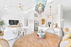 Un salon moderne avec une table ronde en bois, des canapés blancs et un coin repas.