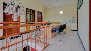 A spacious room with a dining area, a staircase, and a chandelier. - Hotel O Harwin Homestay (Batu)
