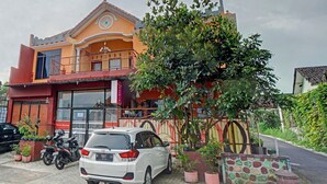 A two-story building with a balcony, a parked car, and potted plants. - Hotel O Harwin Homestay (Batu)