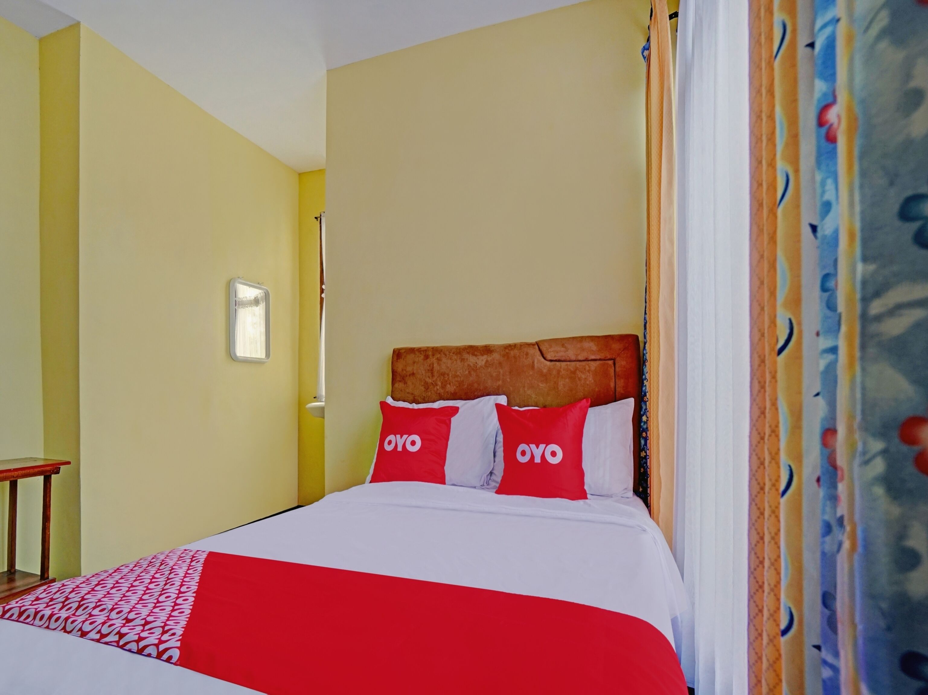 A hotel room with a bed, a nightstand, and a window with curtains.