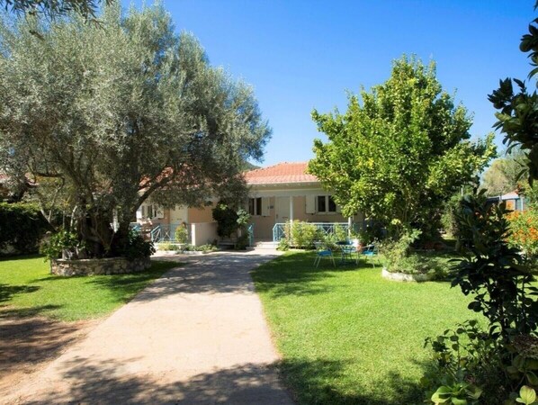 A house with a paved driveway leading to a front door, surrounded by well-maintained grass and trees.