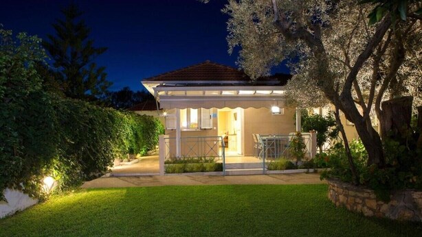 Una casa con patio coperto, prato e un albero.