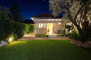 Une maison avec un patio couvert, une pelouse et un arbre.