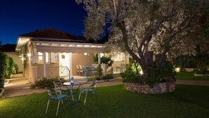 Una casa con patio coperto, area salotto esterna e prato curato.