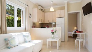 Un ambiente compatto con angolo cottura, zona pranzo e divano con cuscini decorati.