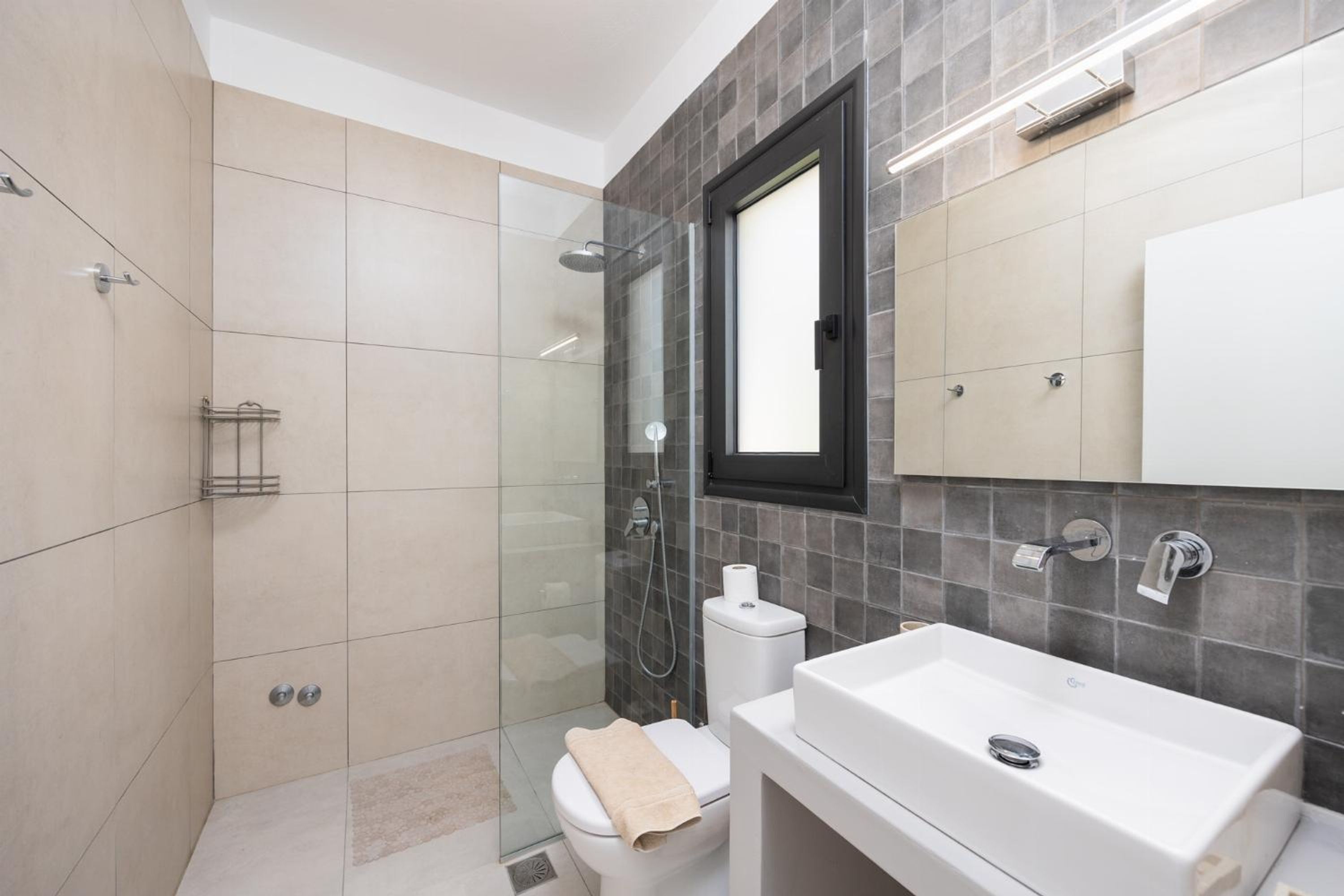 A modern bathroom with a glass-enclosed shower, a white sink, and a toilet.