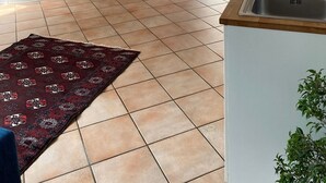 Una cocina con un lavamanos, una mesa de comedor con sillas, un reloj en la pared y vistas al exterior.