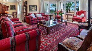 A spacious living room with a red sofa set, a coffee table, and a view of palm trees. - Villa 'Luxury Xenofilia Lll' with Mountain View, Wi-Fi and Air Conditioning (Moraira)