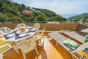 A terrace with a table set for four, surrounded by chairs, overlooking a scenic hillside. - Rincón de María | Near Beach Sea Views Large Terrace BBQ Ideal for Families (Tossa de Mar)