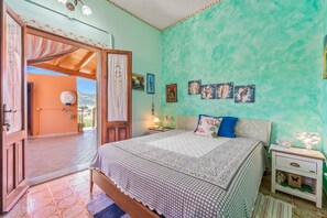 A bedroom with a bed, nightstands, a lamp, and wall art.