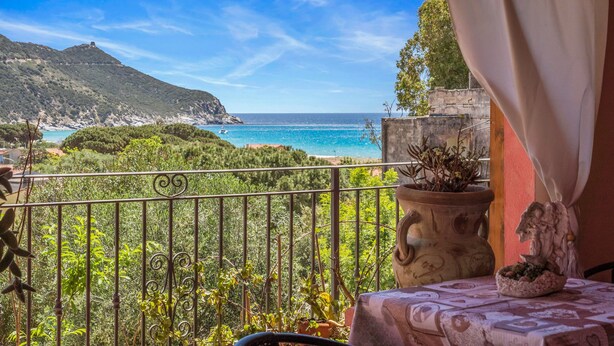 Ein Balkon mit Meerblick, einem Blumentopf und einem Tisch mit Tischdecke.