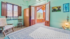 Ein Zimmer mit einem Bett, einem Sessel, einem Kleiderschrank und einer Tür zu einem Außenbereich.