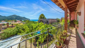 Ein Balkon mit Blick auf das Meer, eine Holz-Pergola und Kübelpflanzen.