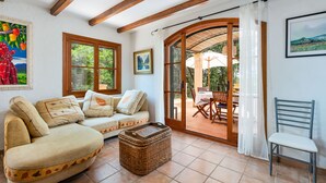 A cozy room with a sofa, a wicker basket, a chair, and a dining area with a table and chairs.