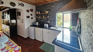 Una cocina moderna con techo de madera, armarios blancos, microondas integrado y un ventanal grande.