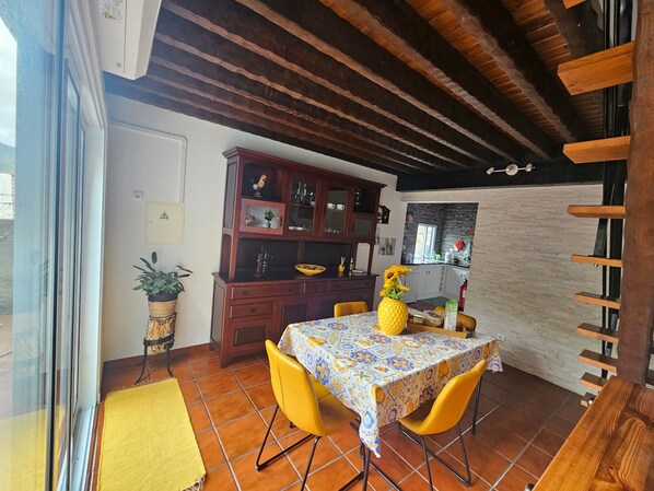 Un comedor con una mesa, sillas, un armario y una planta en maceta.