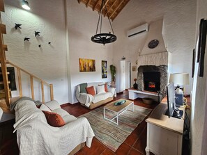 Una sala de estar con chimenea, un sofá, una mesa de centro y un televisor.