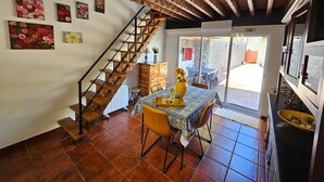 Un área de comedor con escalera de madera, una mesa con sillas y vistas a un patio exterior a través de un ventanal.