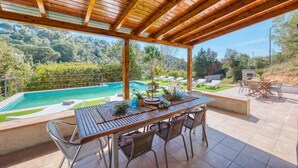 A covered outdoor area with a pool, dining table, and chairs.