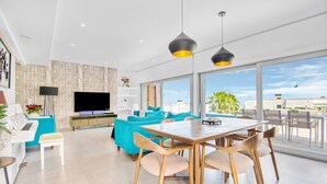 A modern living room with a TV, sofa, and dining area. - Villa "Modern Seaview" with Private Pool & Wi-Fi (Benitachell)