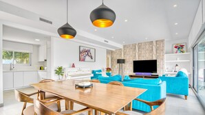 A modern kitchen with white cabinets, a dining table with chairs, a sofa set, a flat-screen TV, and a large window. - Villa "Modern Seaview" with Private Pool & Wi-Fi (Benitachell)