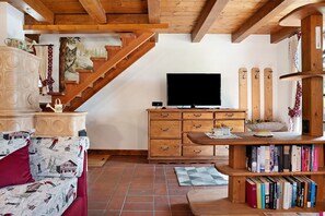 Una escalera de madera, un televisor de pantalla plana, una estantería y un sofá estampado.