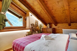 Un dormitorio de cabaña de madera con cama, ventana con cortinas, un reloj de pared y un radiador.