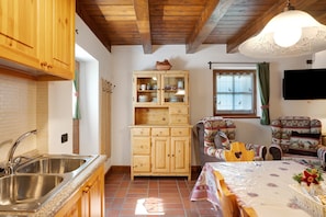A kitchen with wooden cabinets, a sink, and a dining area with a table and chairs.