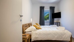 A bedroom with a bed, a desk, a TV, and a window with curtains. - Apartment "Casa Chiarani" with Mountain View, Balcony and Wi-Fi (Arco)