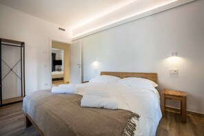 Quarto moderno com cama grande, mesas de cabeceira, guarda-roupa e espelho.
