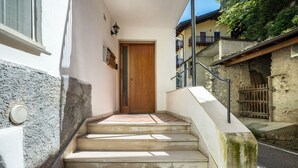 A staircase leading to a wooden door, a stone wall, and a metal railing. - Apartment "Casa Chiarani" with Mountain View, Balcony and Wi-Fi (Arco)
