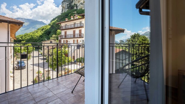 A balcony with a view of a mountain, a parked car, and a building with balconies. - Apartment "Casa Chiarani" with Mountain View, Balcony and Wi-Fi (Arco)